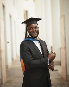 a man in a graduation cap and gown posing for the camera with his arms crossed