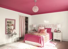 a bedroom with pink and white decor on the walls, carpeted flooring and furniture