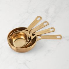 gold measuring cups and spoons sitting on a marble counter top with the handles down