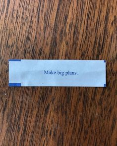 a piece of paper that says make big plans on it sitting on top of a wooden table