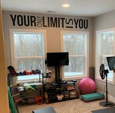 a living room filled with lots of furniture and a wall mounted tv next to two windows