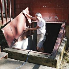 a man is working on an old metal door in the back of a building that has been gutted