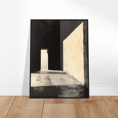 a black and white painting sitting on top of a wooden floor next to a wall