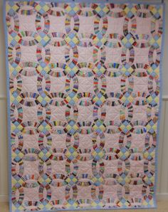 a pink and blue quilt hanging on the wall