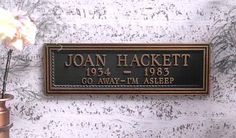 a plaque that says joan hackett on it next to a vase with flowers