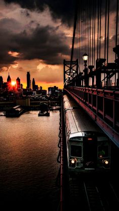 a train traveling across a bridge next to a large body of water in front of a city