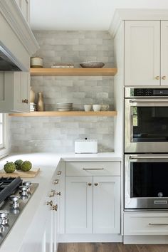 a kitchen with white cabinets and stainless steel stove top oven, built in shelving