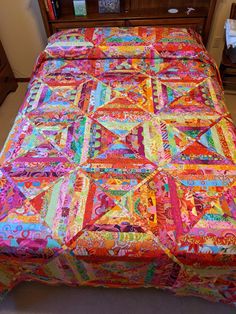 a bed with a colorful quilt on top of it