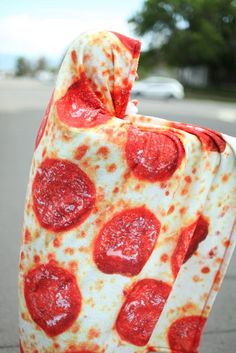 a piece of pizza sitting on top of a parking meter covered in a blanket that has been made to look like a pepperoni pizza