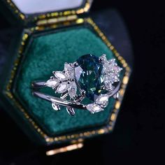 a blue diamond ring sitting in a green velvet box