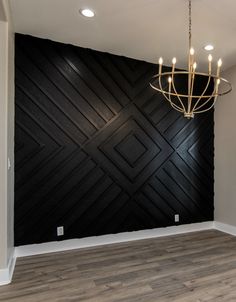 an empty room with a chandelier hanging from the ceiling and wood paneling on the wall