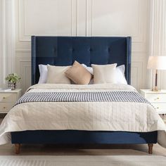 a bed with blue upholstered headboard and pillows