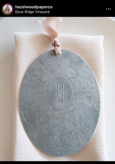 a white plate with a monogrammed design on it and a pink ribbon around the edge