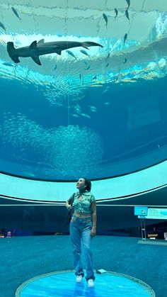 a woman is standing in front of an aquarium