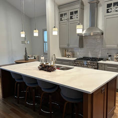 a kitchen island with four stools next to an oven and sink in the center