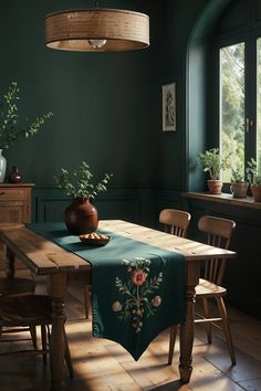 a dining room with green walls and wooden table in the center, surrounded by potted plants