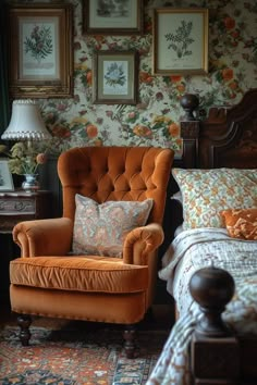 an orange chair sitting in front of a bed next to a lamp and pictures on the wall