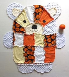 a teddy bear made out of patchwork material with an orange ball on the floor