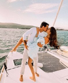 a man and woman kissing on the back of a boat