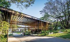 the entrance to an outdoor pavilion surrounded by trees and grass, with a car parked in front