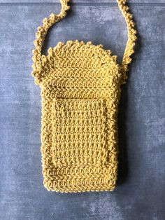 a yellow crocheted purse sitting on top of a gray table next to a black wall