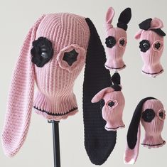 a pink knitted hat and mittens with black ears are on display in front of a white background