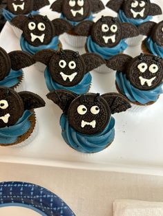 cupcakes decorated with black and blue icing are sitting on a white tray