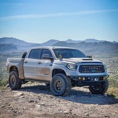 a silver truck parked on top of a dirt hill