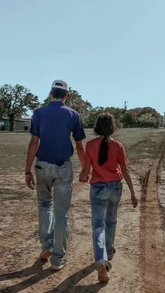 a man and woman walking down a dirt road