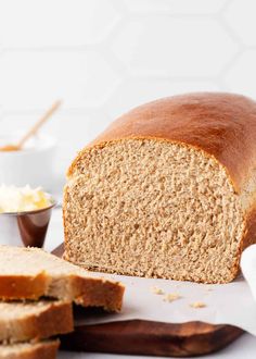 a loaf of bread sitting on top of a cutting board next to butter and spoons