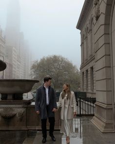 a man and woman holding hands walking in the rain