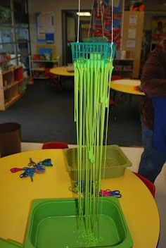 a green vase sitting on top of a yellow table in a room filled with children's toys