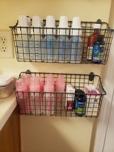 two metal baskets filled with bottles on top of a bathroom counter next to a sink