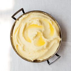 a pan filled with mashed potatoes on top of a white tablecloth next to a knife