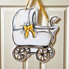 a baby's carriage ornament hanging on a door with a yellow ribbon