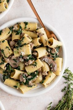 two white bowls filled with pasta and mushrooms