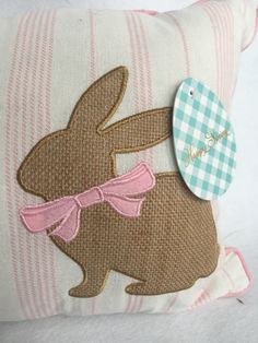 a decorative pillow with an embroidered bunny on it