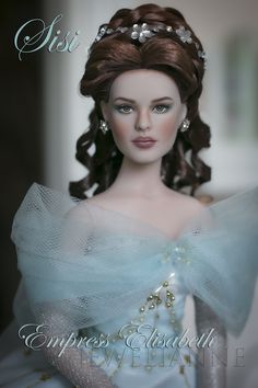 a close up of a doll wearing a blue dress with pearls on it's head