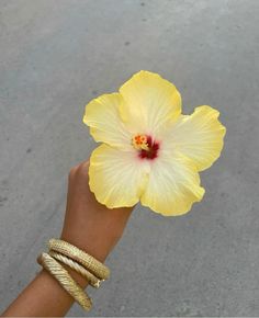 a person's hand with a yellow flower on it