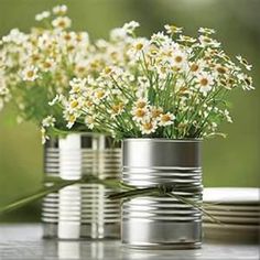 some white flowers are in tin cans on a table