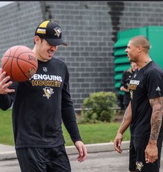 two men standing next to each other with a basketball in their hands and one man holding a ball