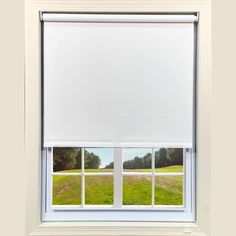 an open window with white roller shades on the windowsill and grass in front of it