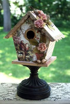 a birdhouse with flowers on it sitting on a table