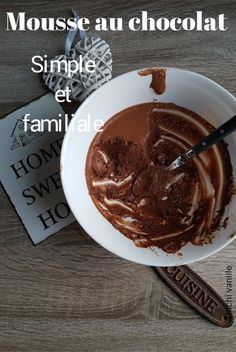 a white bowl filled with chocolate on top of a wooden table next to a book