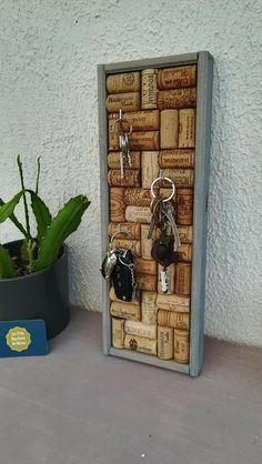 a wine cork key holder with several keys hanging from it and a potted plant next to it