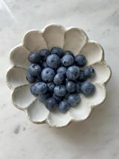 a white bowl filled with blueberries on top of a table