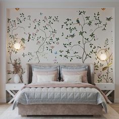 a bed sitting under a wall with flowers and birds on it's headboard