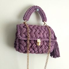 a purple handbag hanging on the wall with chains attached to it's handles