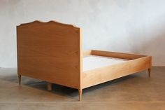 a wooden bed frame sitting on top of a cement floor next to a white wall