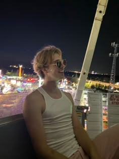 a man sitting on top of a roof next to a tall pole with lights in the background